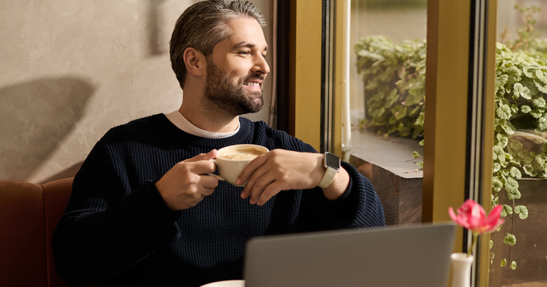 Mature man with coffee looking out a cafe window, comparing TMS vs ECT for treatment-resistant depression